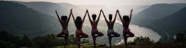 A group of women of color practicing mindful movement together in a misty mountain valley