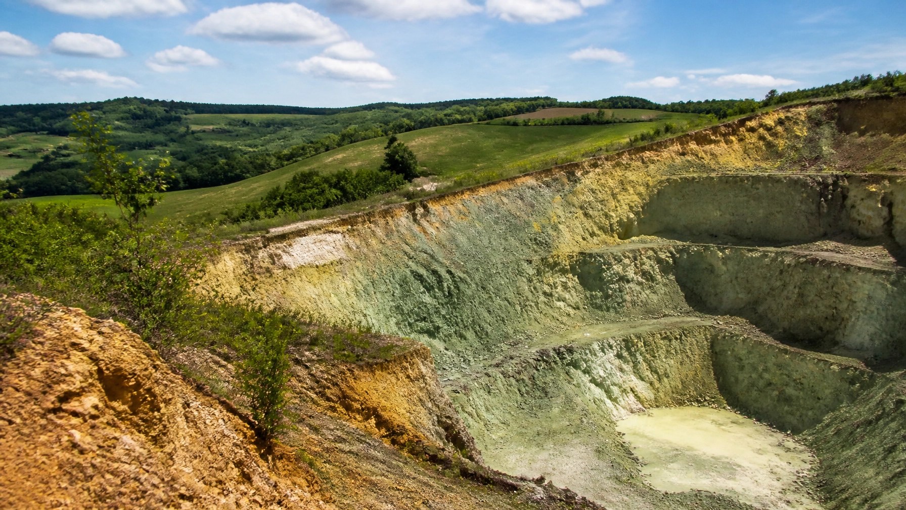 A natural clay quarry in the French countryside with rolling green hills