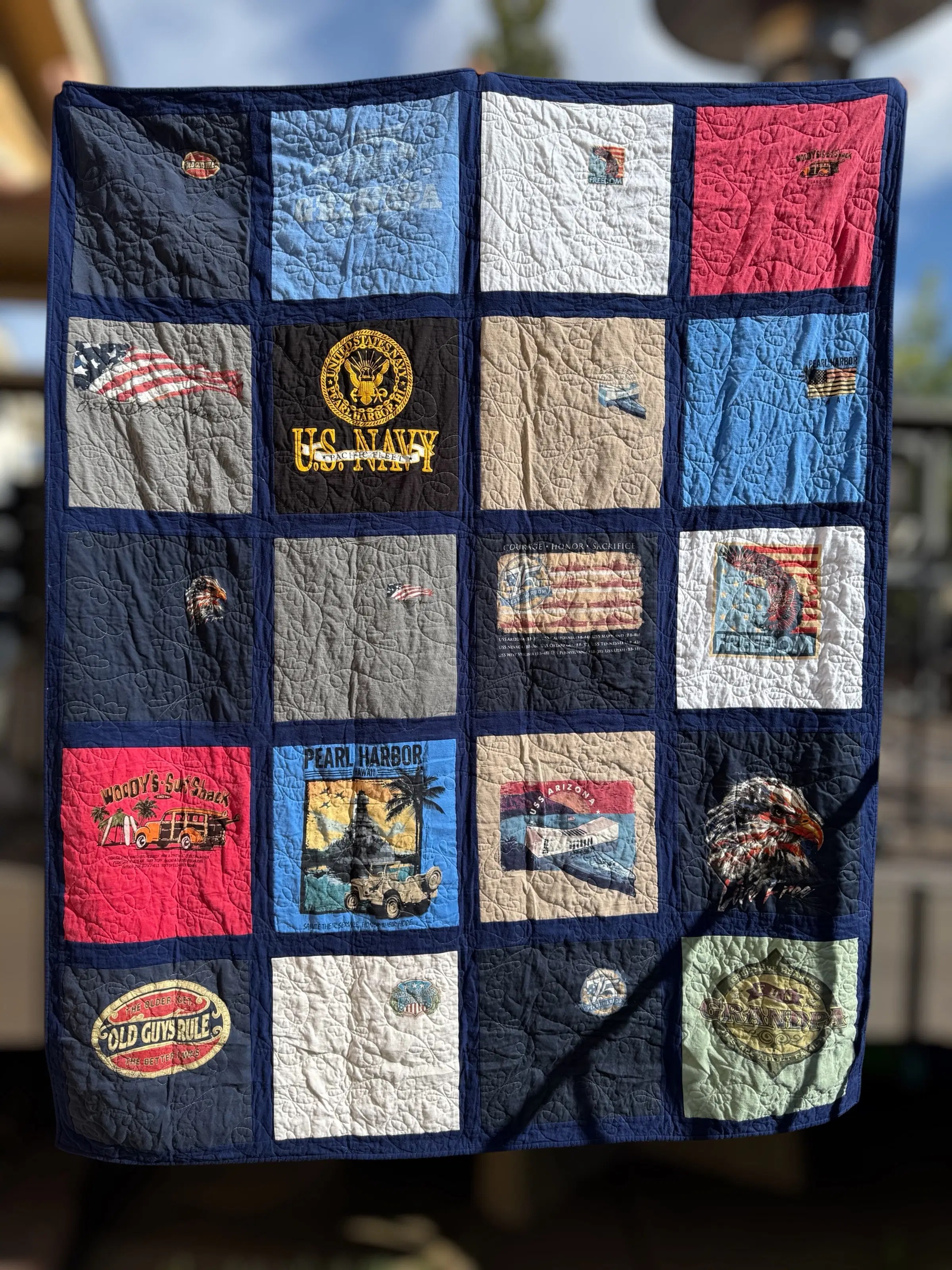 A beautiful finished Navy-themed T-shirt quilt featuring commemorative patches and patriotic designs.