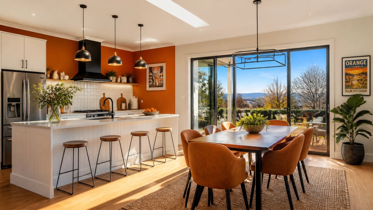 A wide shot of a modern kitchen and dining area in Orange NSW with large windows showing a sunny winter day and vibrant interior walls.