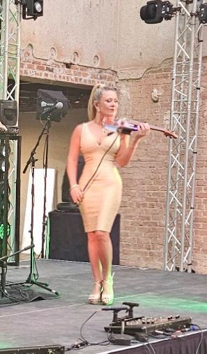 Carrie Caruso performing on stage with dramatic truss lighting, creating a high-impact luxury event atmosphere.