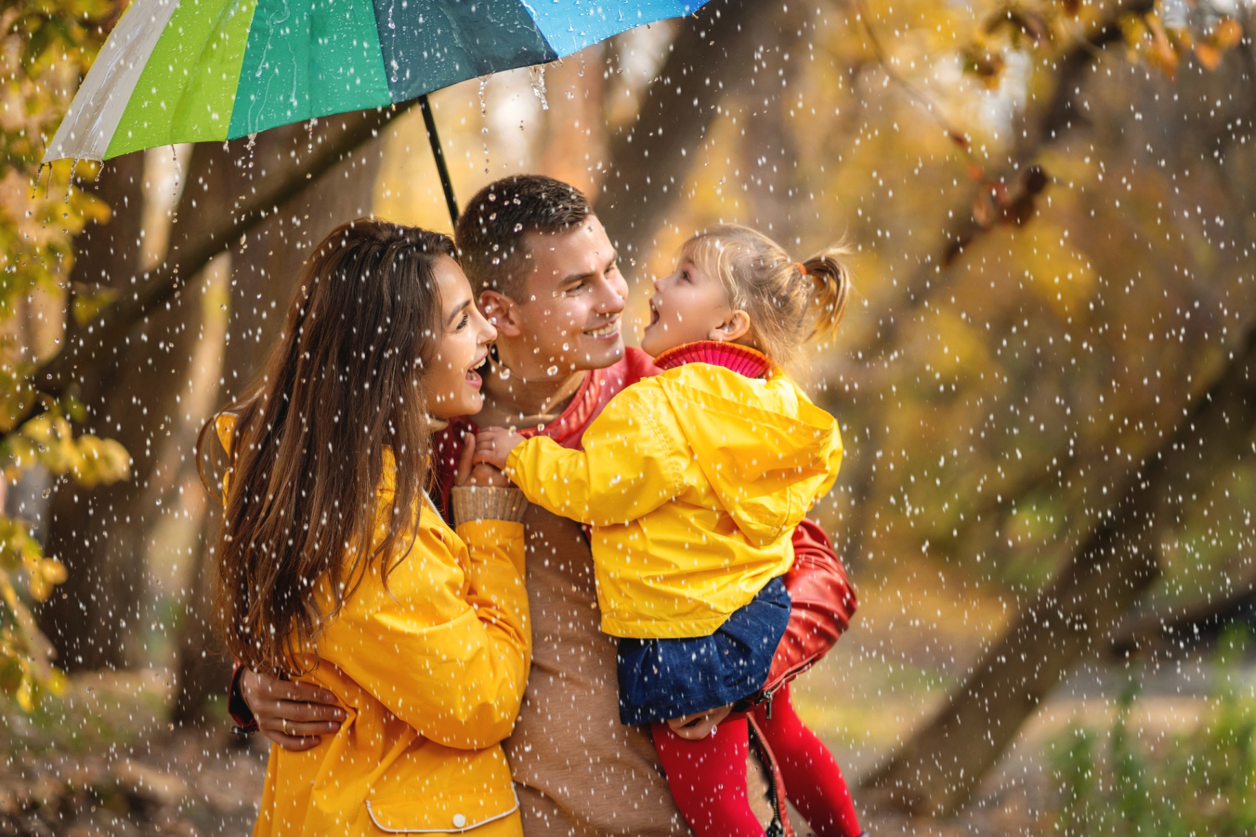 Family portrait session outdoors with colorful fall leaves and a playful umbrella