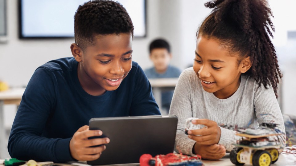 A young black boy and girl collaborating on a tablet and creative tech project together, showing future career readiness and digital learning.