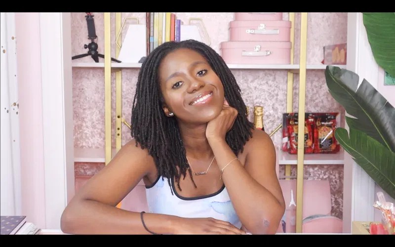 A woman radiating confidence at a pink-accented workspace, scripting her future relationship with high-caliber intention.