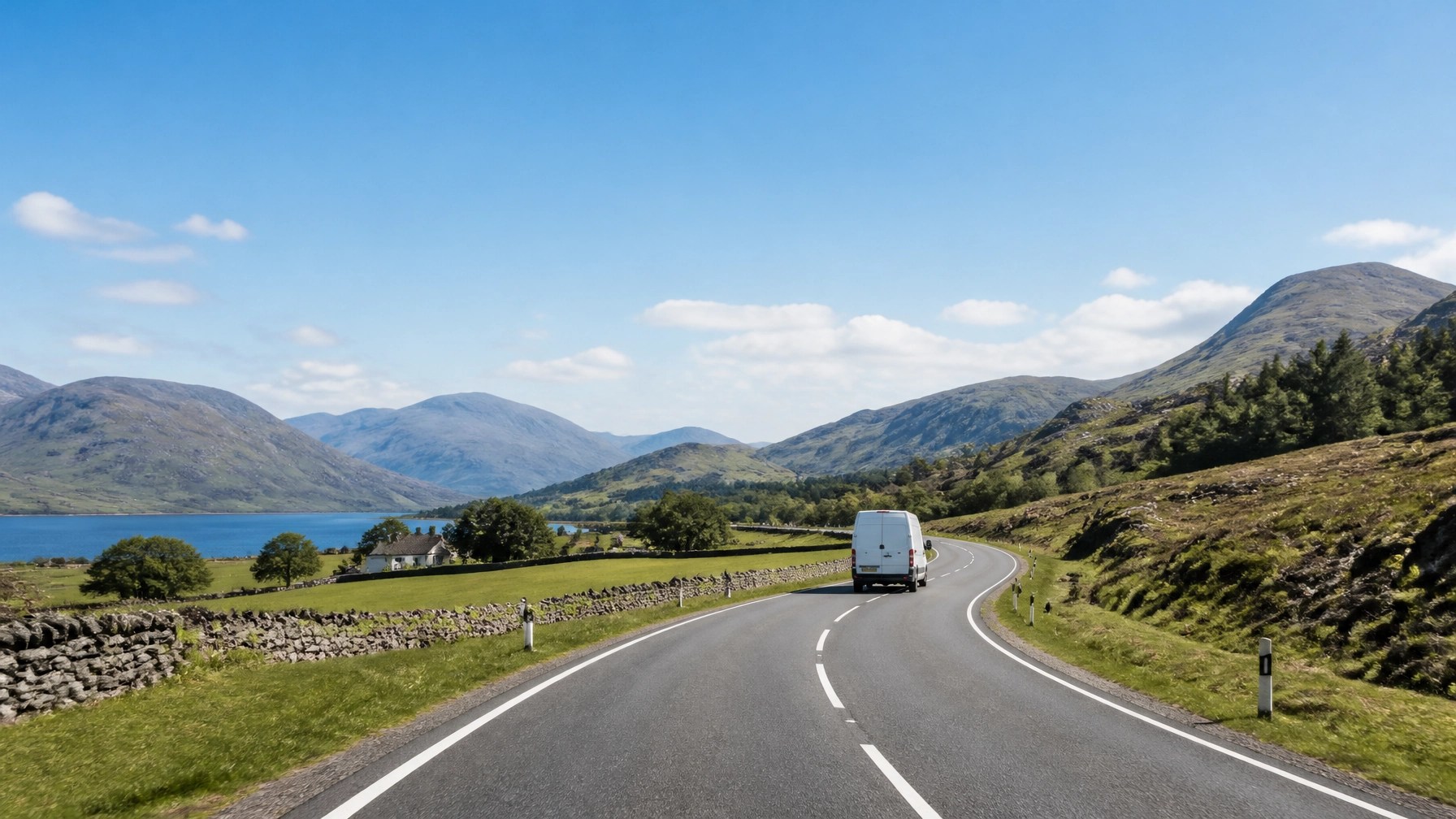 A white transport van on a peaceful rural road under a bright sky