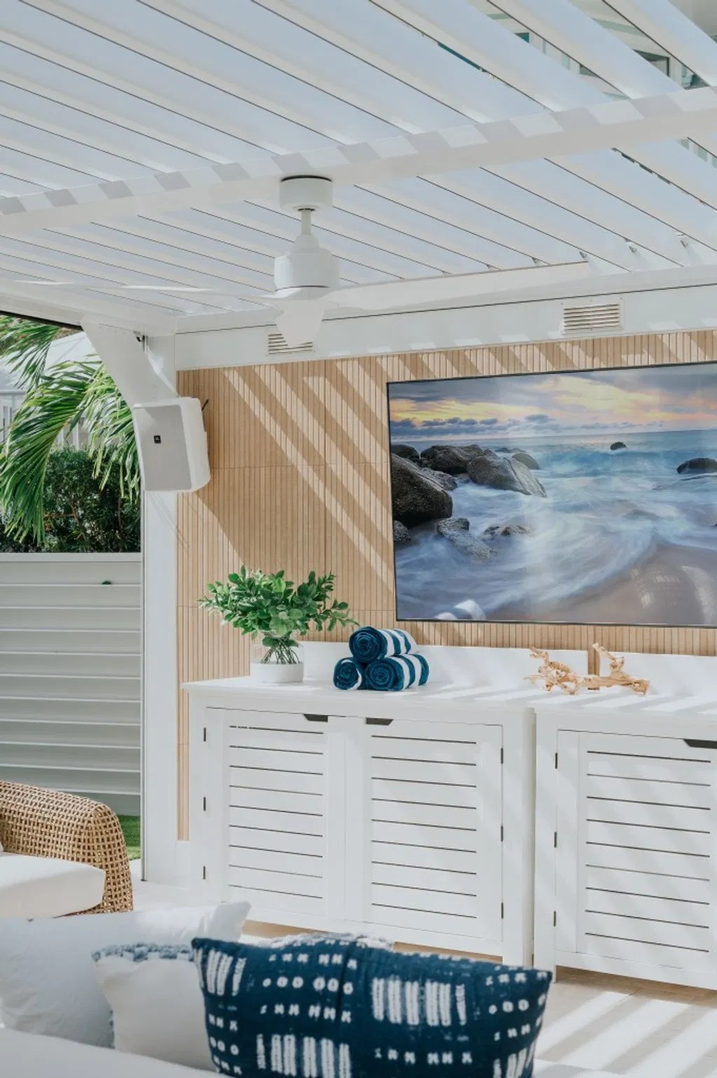 A modern outdoor living area with a white motorized louvered roof system, custom cabinetry, and a mounted TV, designed for South Florida family time, game-day entertaining, and seamless indoor-outdoor relaxation.