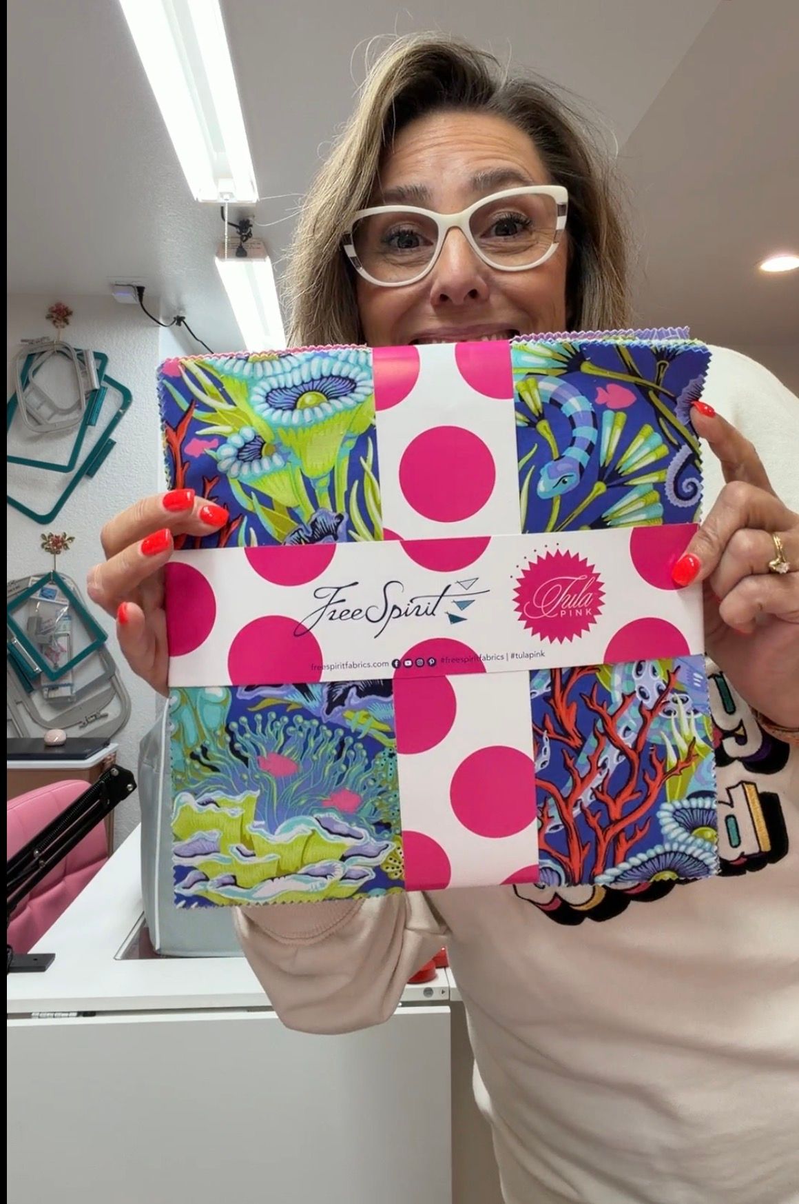 Anisa holding a bundle of beautiful fabrics, looking inspired and ready to start a new project.