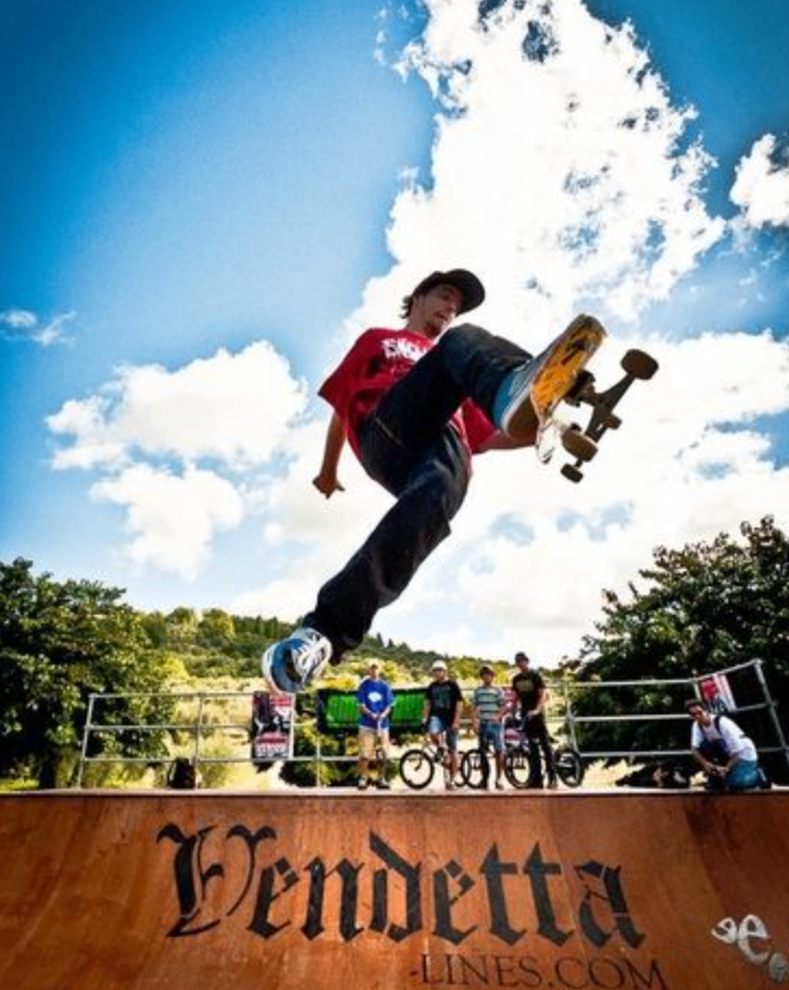 A skateboarder executes a high jump trick on a half pipe