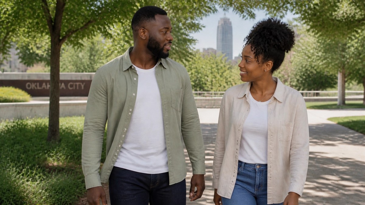 A Black couple walking together in an Oklahoma City park, looking relaxed and happy.