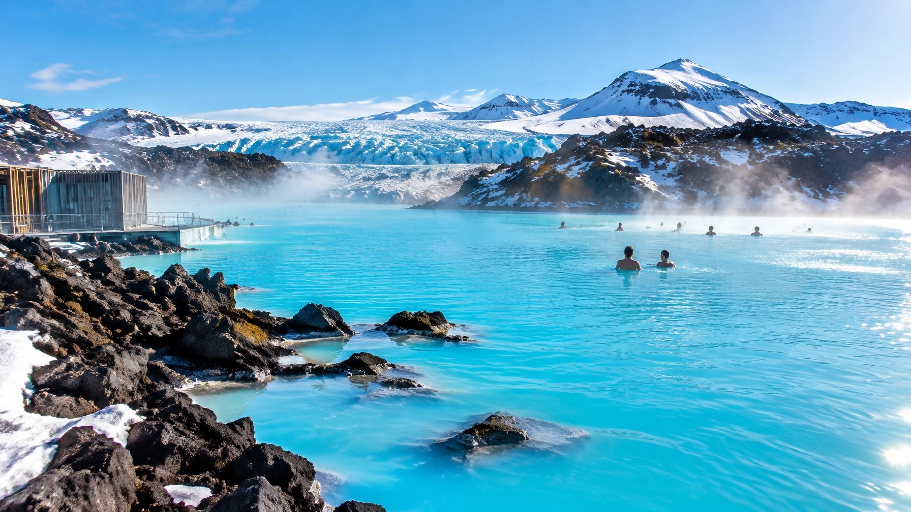 Turquoise geothermal lagoon beside a glacier and black volcanic landscape in bright Icelandic winter sunlight