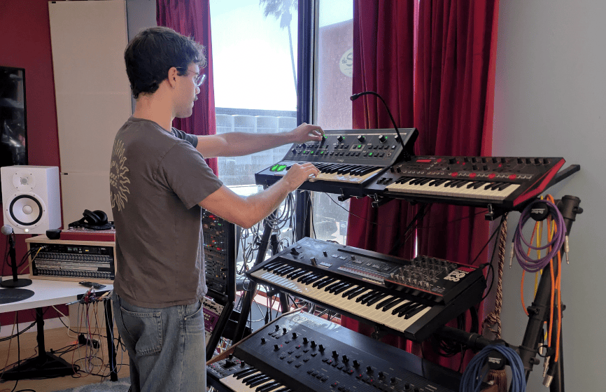 Producer working with a rack of synthesizers in Studio B.