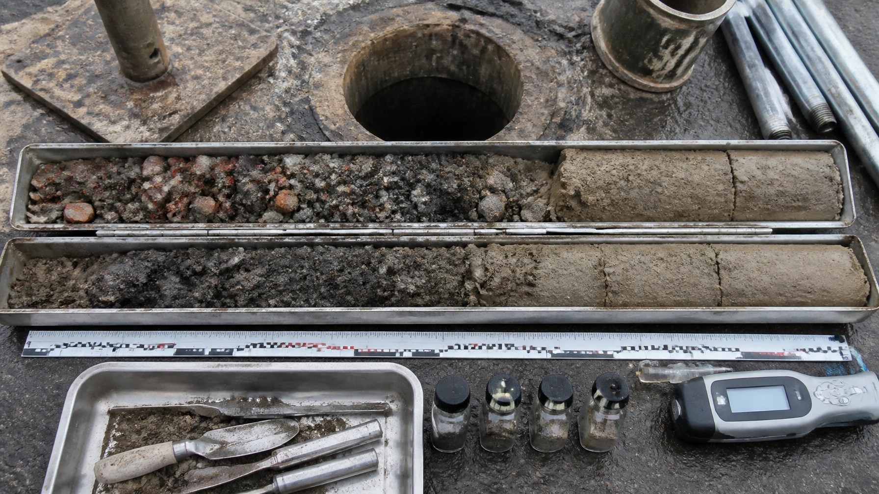 Geotechnical soil core transitioning from heterogeneous urban fill to native soil with sampling equipment