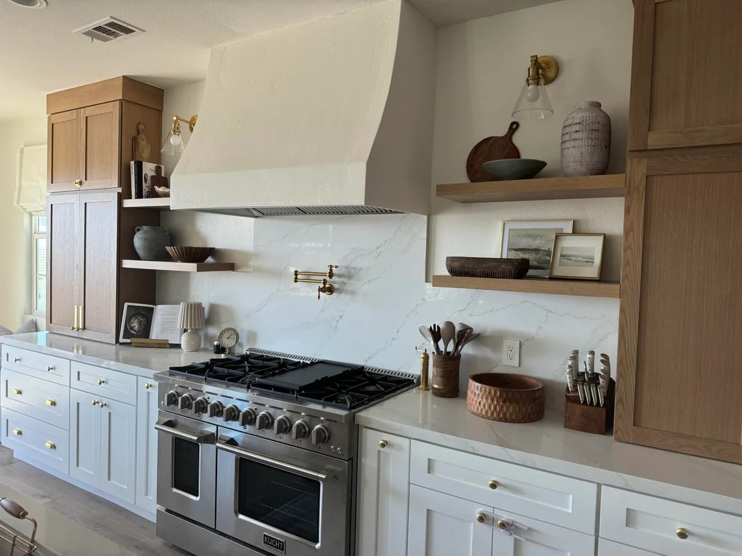 Custom kitchen remodel featuring white shaker cabinets with brass hardware, sleek marble-look countertops, and premium stainless steel appliances.