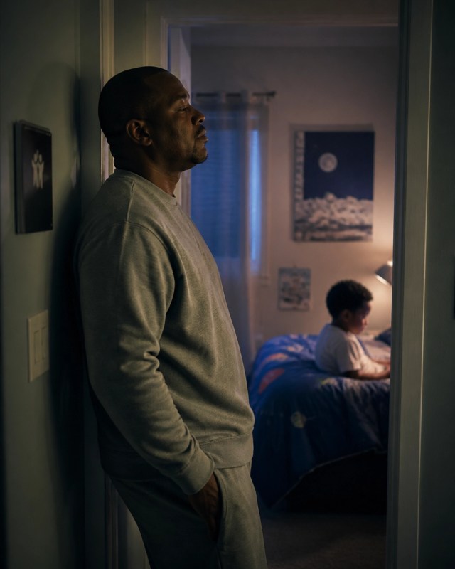 A father pausing in a hallway after a difficult conversation and preparing to return with humility
