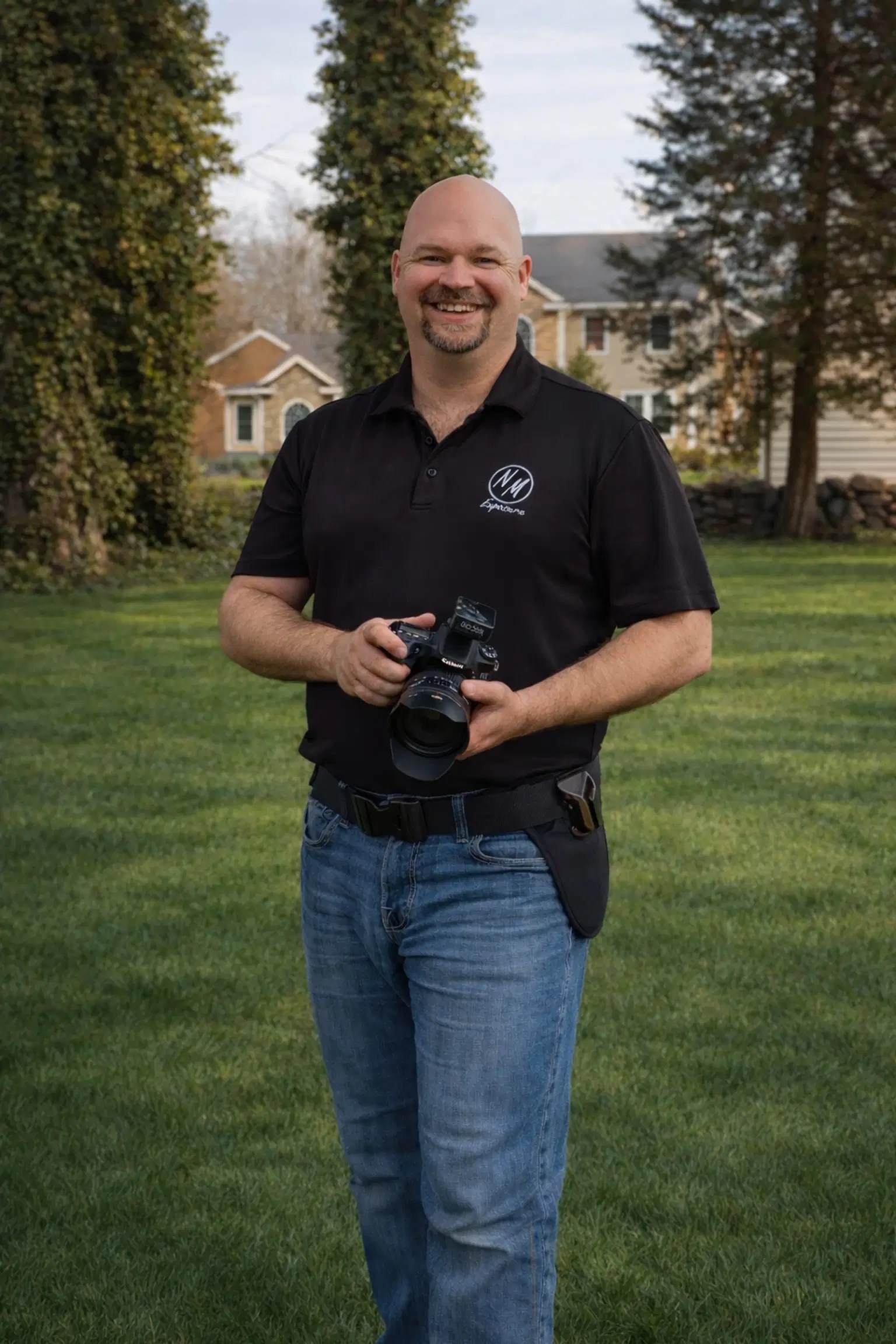 Mike, our resident goofball, smiling outdoors with his camera and utility belt