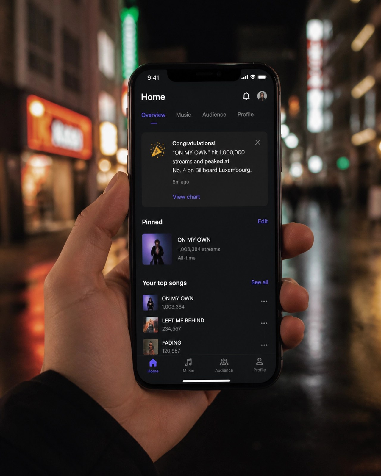 An artist holding a smartphone showing a 1M stream milestone and a No. 4 Billboard placement.