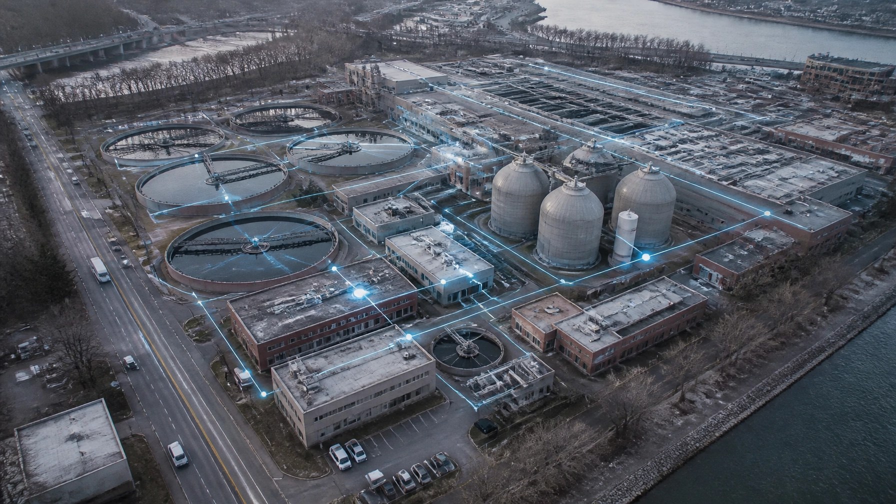 Aerial view of a Northeastern wastewater treatment plant with abstract protected network zones connecting SCADA, pumps, and sensors