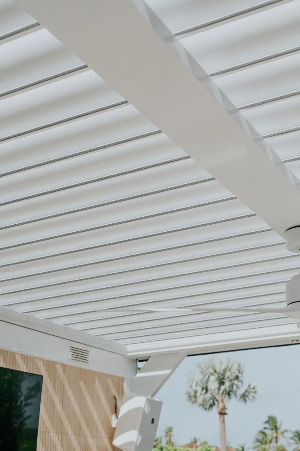 Close-up architectural view of adjustable white louvered roof blades with integrated outdoor living details