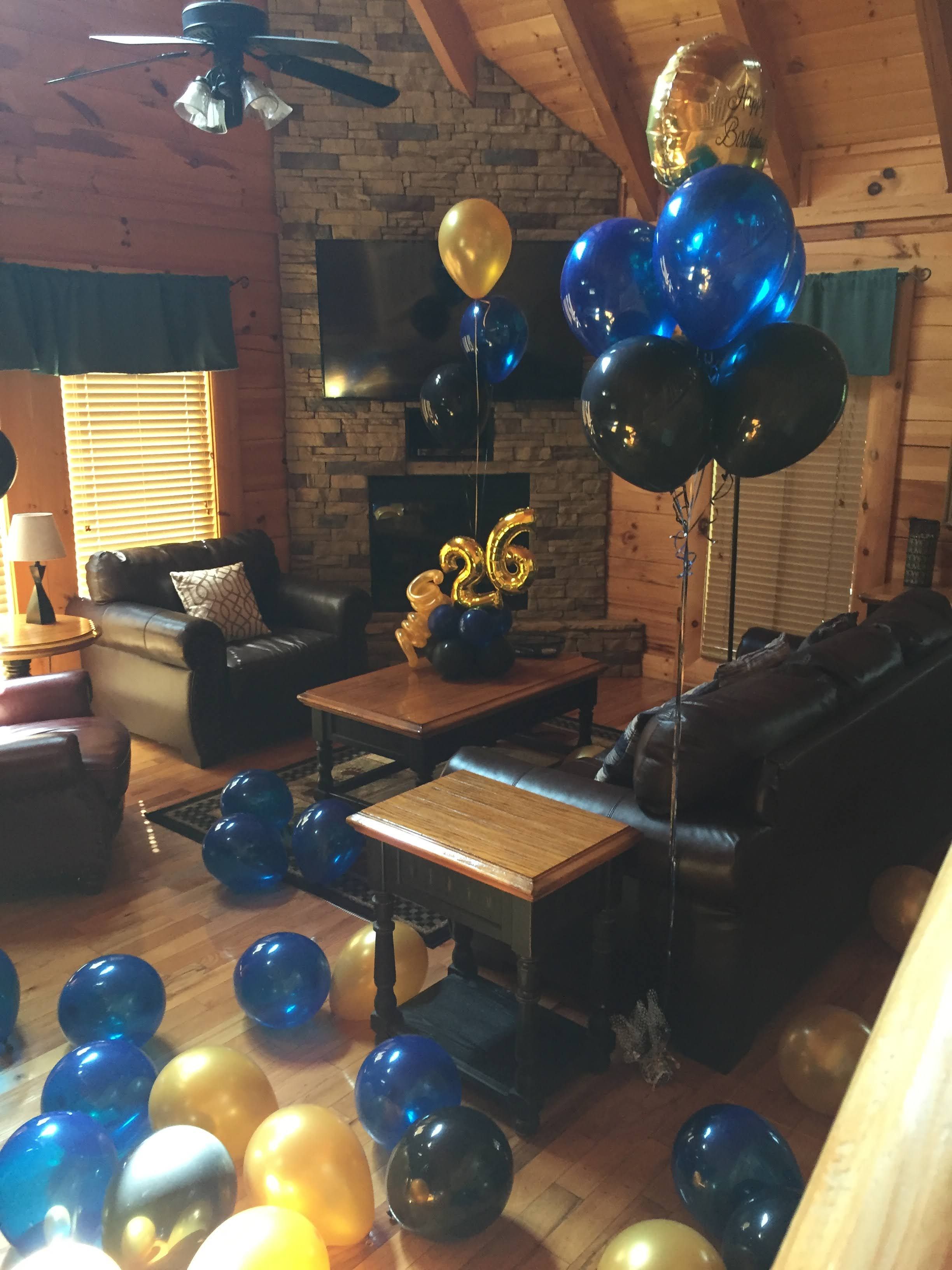 A sophisticated 26th birthday decoration setup with blue and gold balloons inside a rustic mountain cabin
