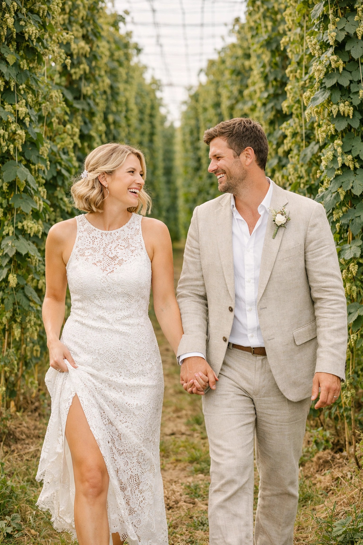 Bride and groom walking through a traditional Kentish hop garden during their homecoming wedding party.