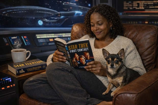 A woman reading Star Trek First Contact and Federation books with a cup of coffee and Ethel resting nearby.
