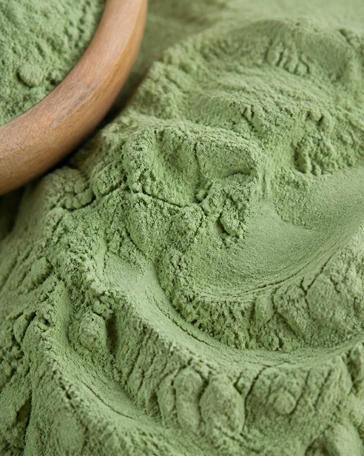 A macro close-up of fine, soft green clay powder.