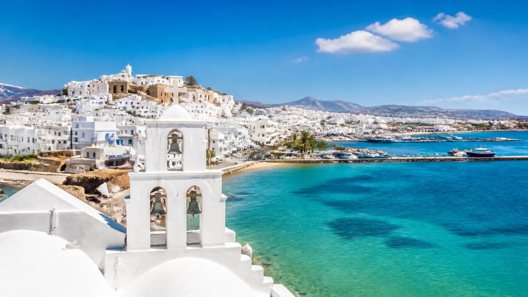 Bright daytime view of Naxos whitewashed architecture under brilliant blue sea