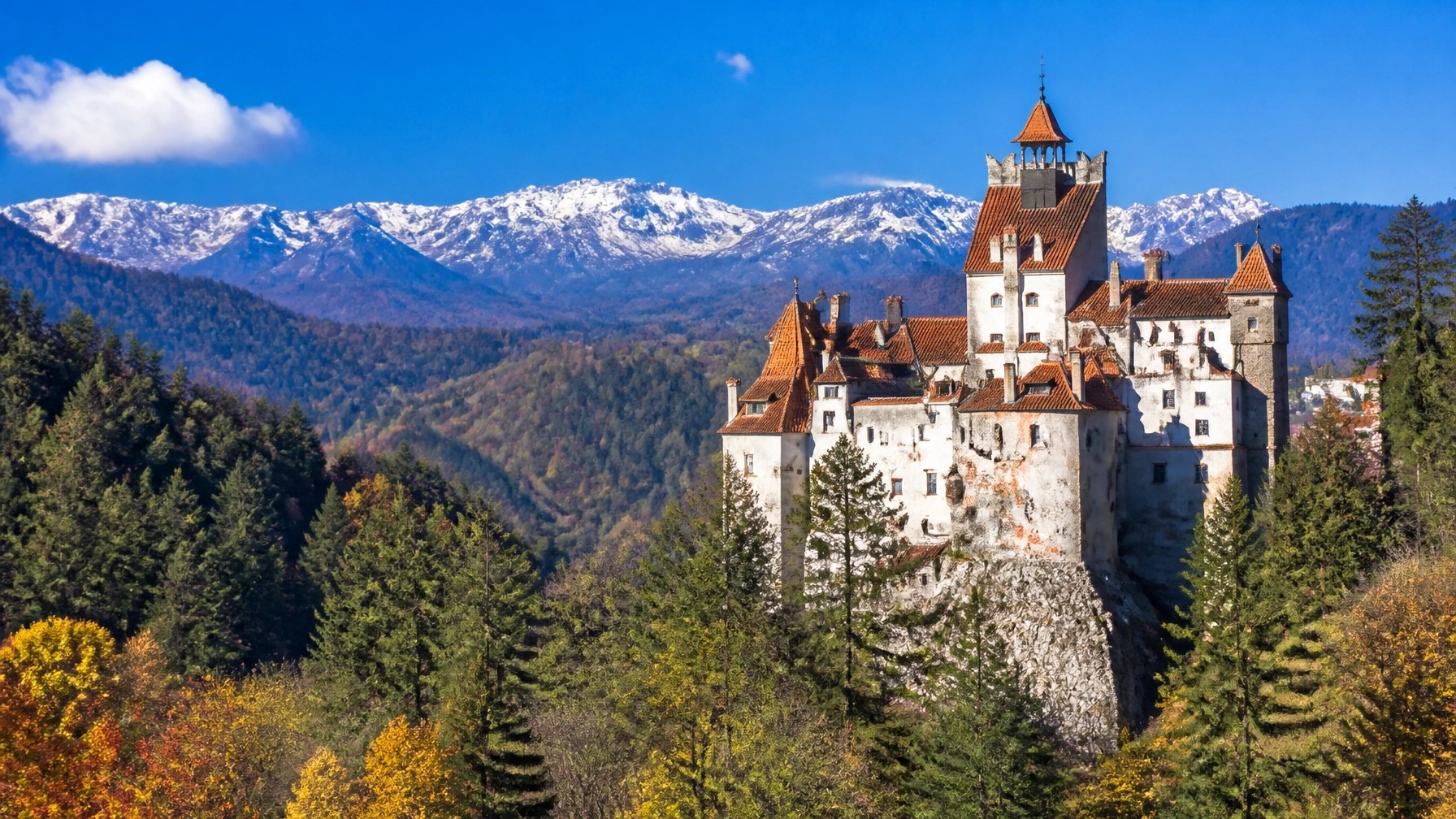Bran Castle surrounded by autumn colour and Carpathian scenery in daylight