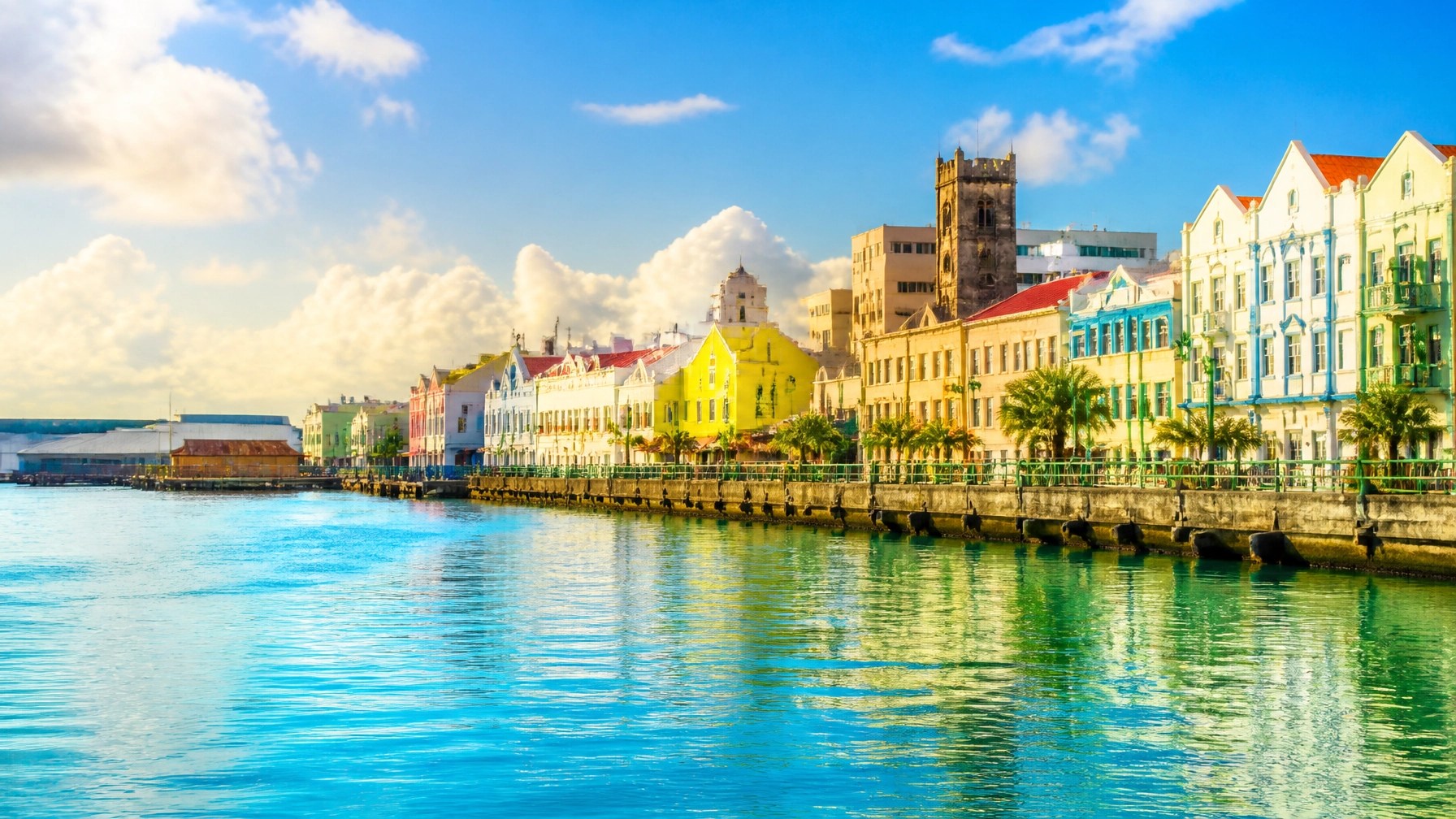 Scenic Bridgetown waterfront in Barbados with historic buildings, palm-lined shore, and calm Caribbean water
