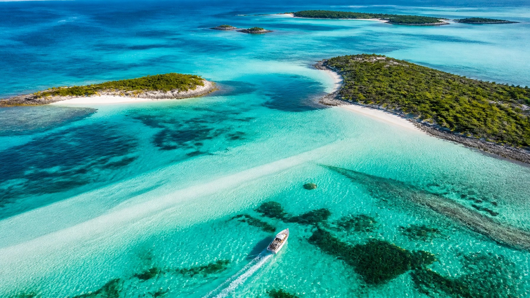 Sleek unoccupied boat gliding between white sandbars and emerald Bahamian cays