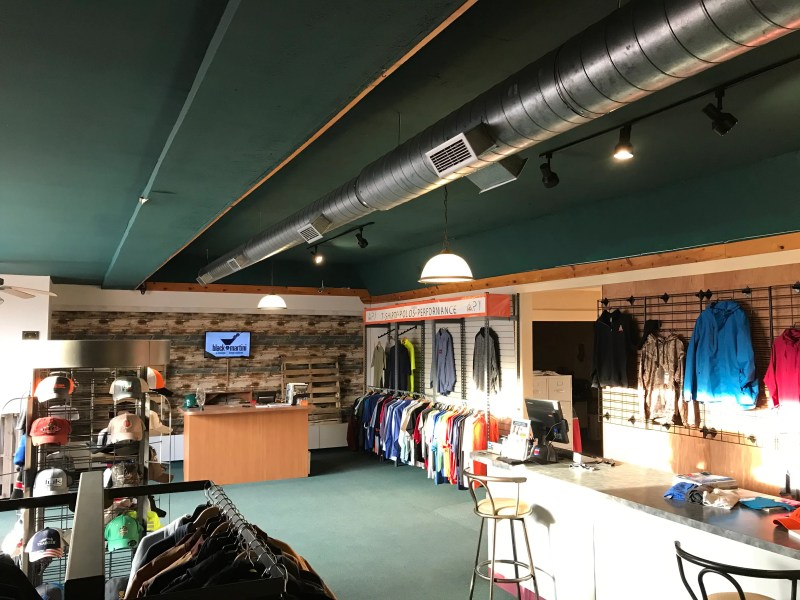 A display of custom-branded hats and performance masks on a clean, modern shelf in a bright showroom
