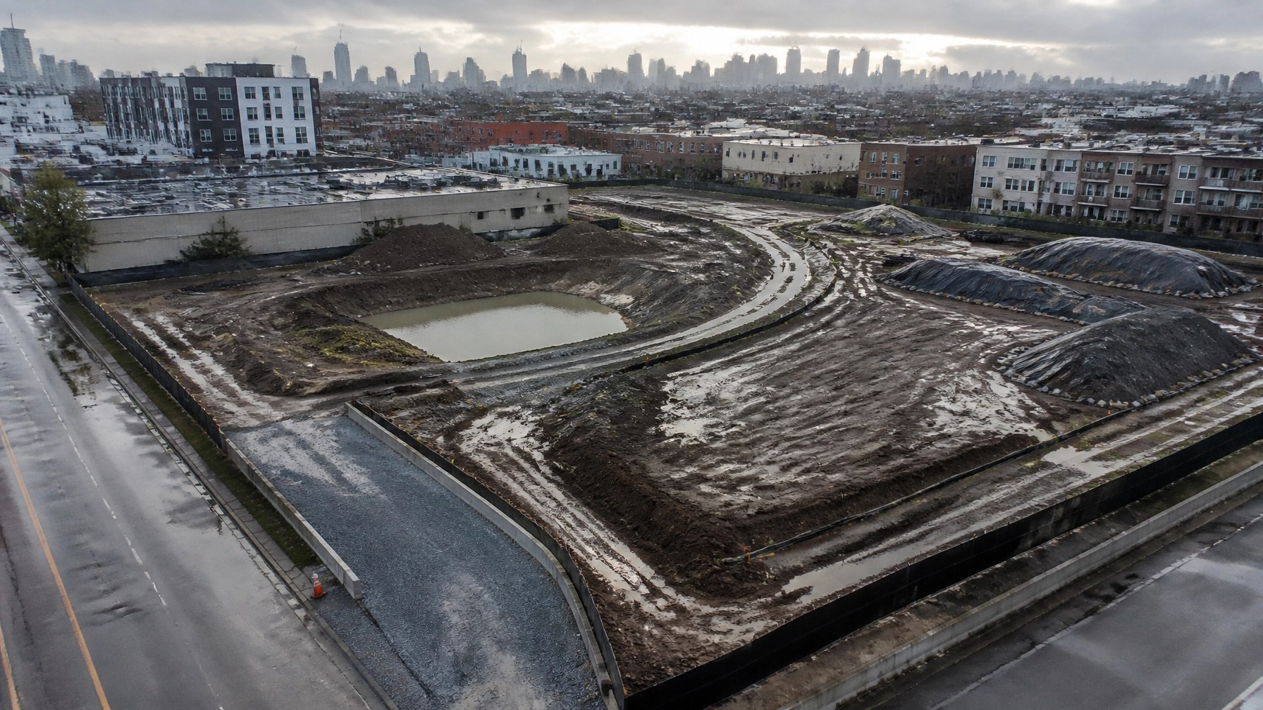 Aerial view of an urban construction site showing temporary swales, sediment basin, silt fencing, and stabilized access