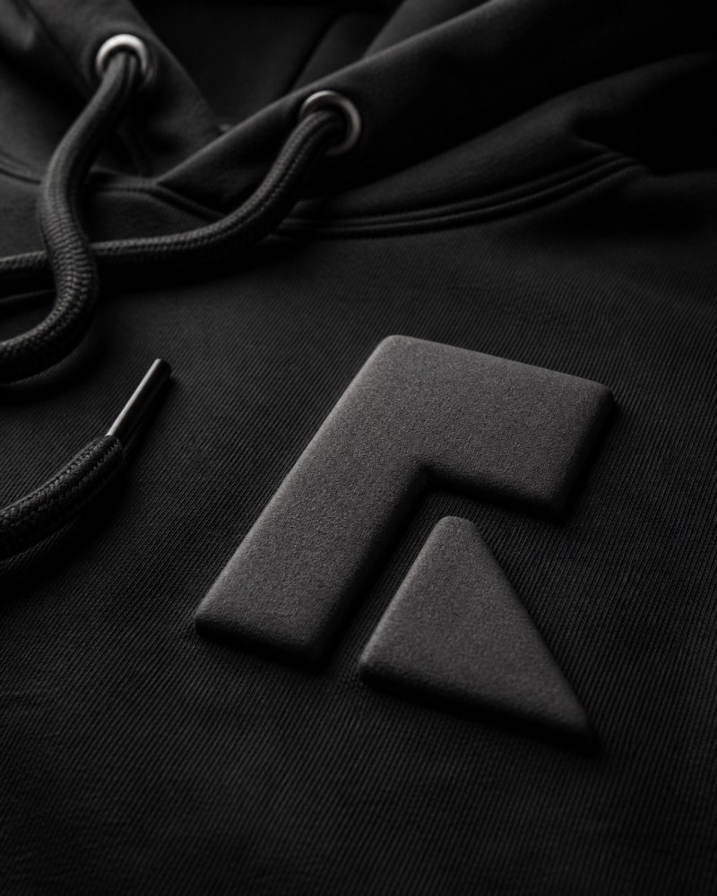 A macro shot of a black custom hoodie featuring a minimalist 3D Puff Ink design with a tactile, matte finish.