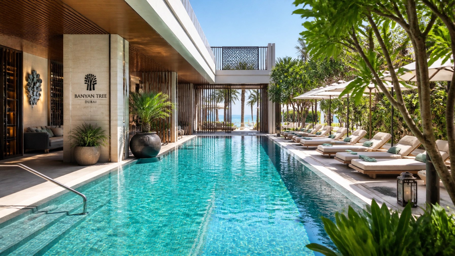 Bright daytime modern resort pool interior on Bluewaters Island with elegant architecture, shaded loungers and glimpses of sea