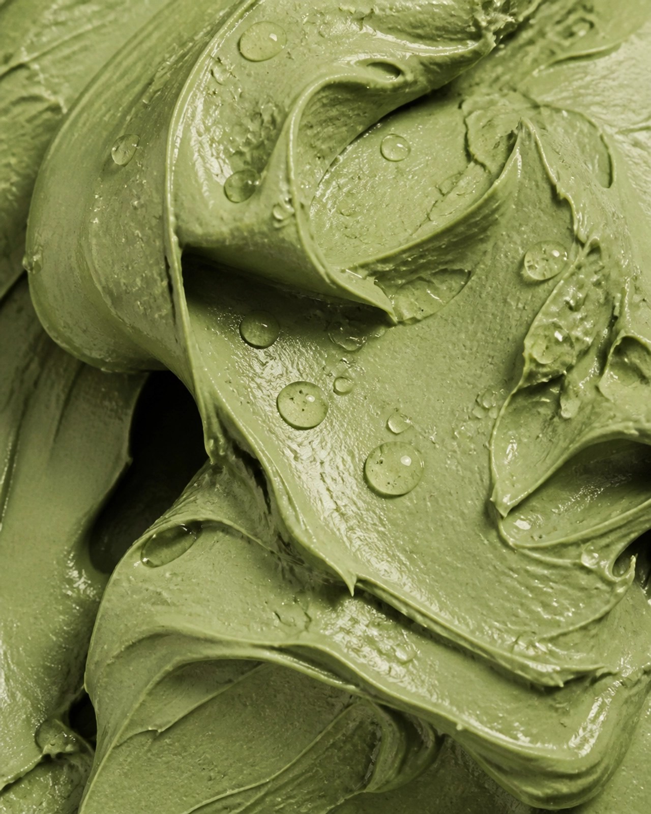 A macro close-up photo of natural French green clay showing its velvety texture and mineral swirls.