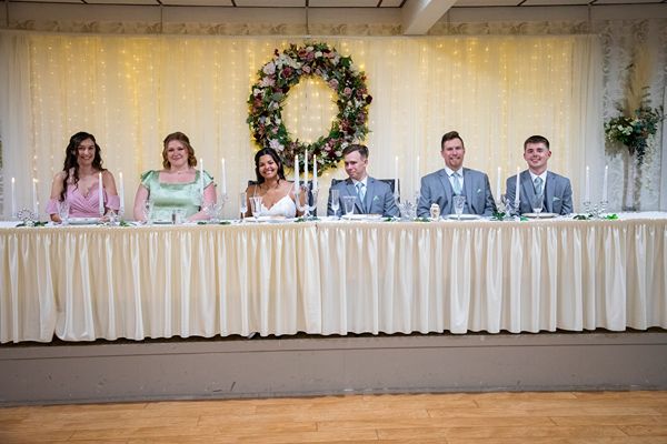 Wedding venue near Iowa City banquet hall setup at Price Creek Event Center in Amana, Iowa—wedding party seated at an elegant head table with candlelight and greenery