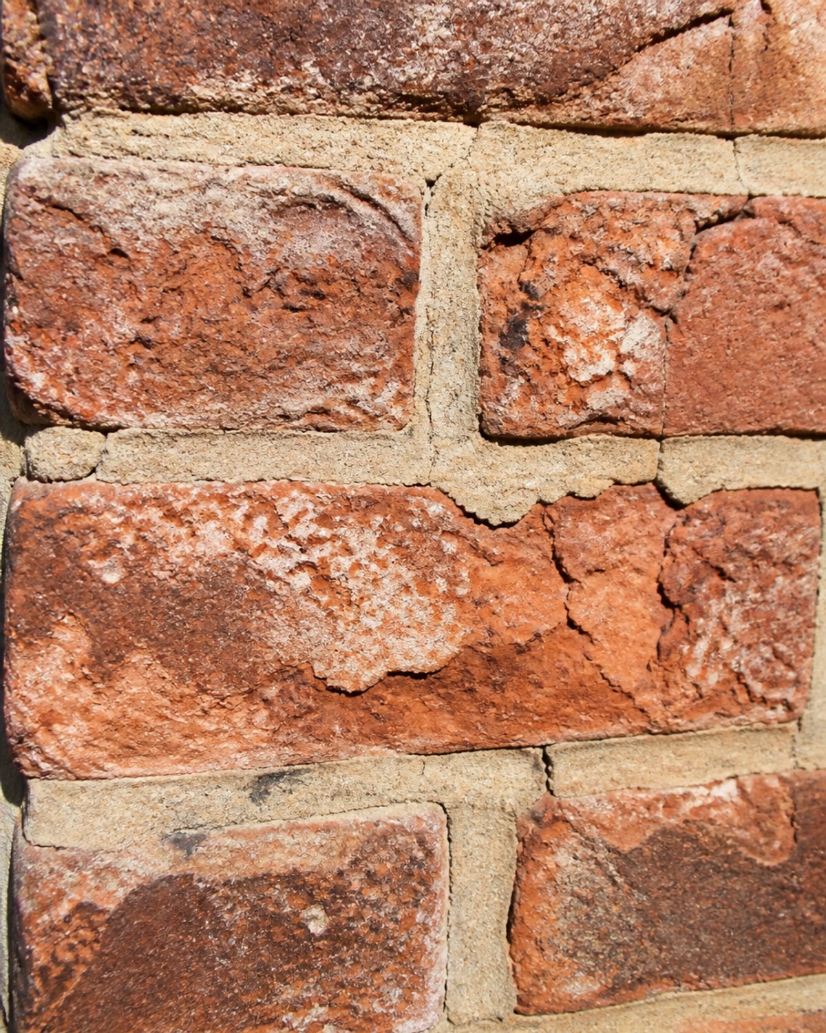 A close-up of weathered heritage brick and mortar showing spalling and cracks