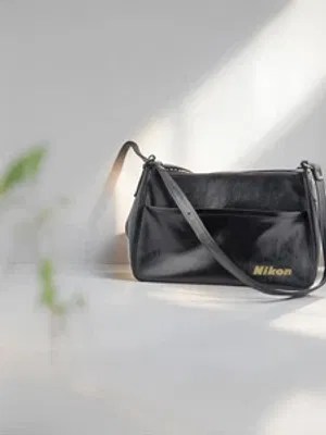 A black Nikon-branded camera shoulder bag, symbolizing the care and transportation of electronics for repair or recycling
