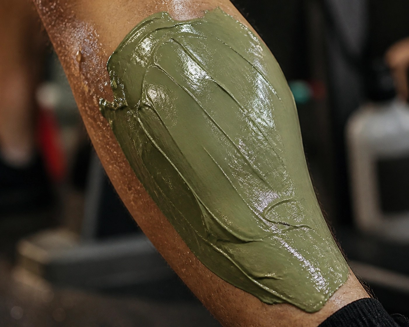 Thick application of moist green healing clay on an athlete’s muscle for inflammation relief.