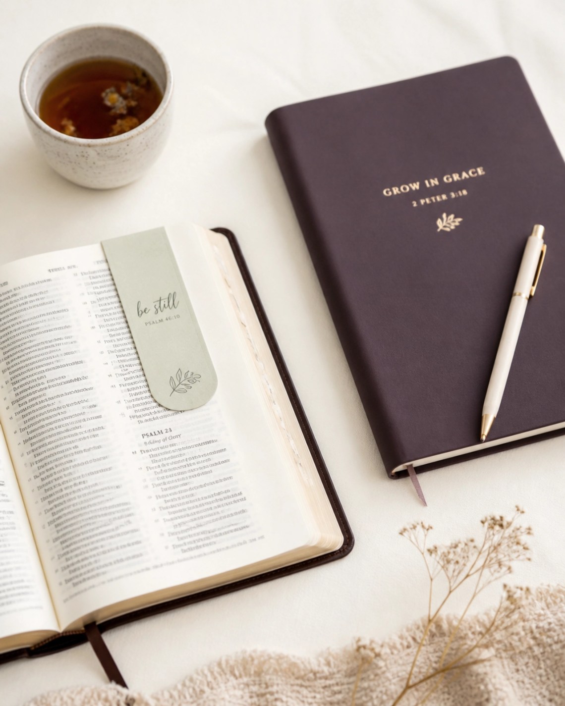 A flat lay of spiritual growth tools: an open Bible with a Misty Sage magnetic bookmark and a prayer journal on a soft cream surface.
