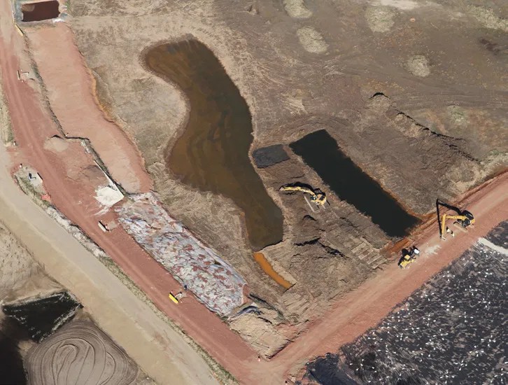Aerial view of an active brownfield remediation site featuring open soil excavations and water management.