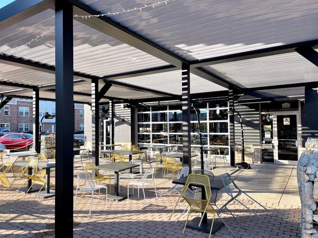 A modern covered patio and restaurant-style outdoor dining area with contemporary seating and a refined open-air layout