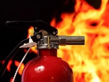 Close-up of a red fire extinguisher with safety seal, highlighting workplace fire safety readiness and compliance