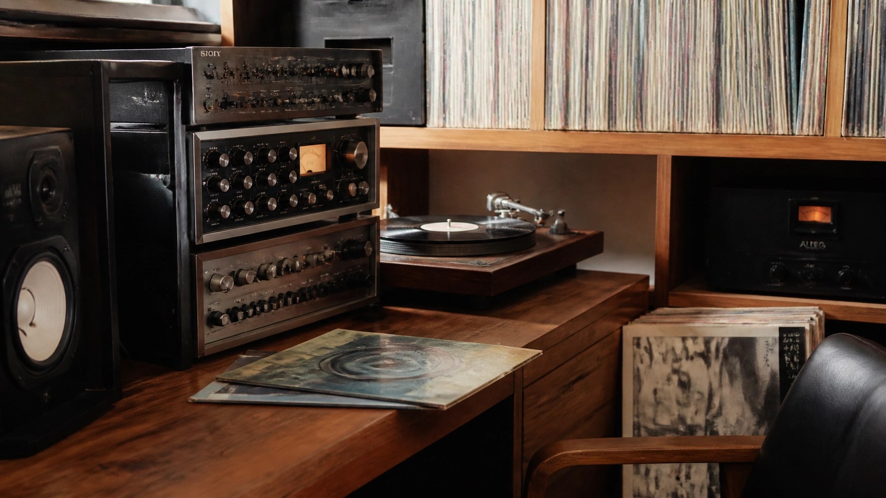 Vintage vinyl records and professional audio equipment on a sleek wooden studio desk