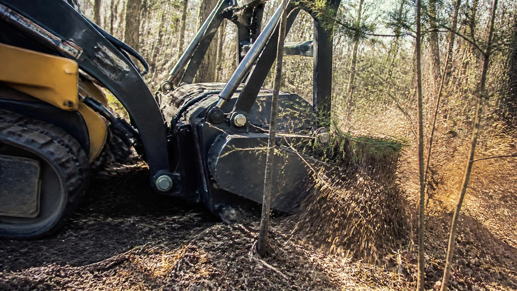 Authentic close-up field photography of a brand-neutral forestry mulching head engaging brush and stump material on a Wisconsin hunting property in real daylight, showing flying wood chips, bark texture, mud, and natural forest conditions with a raw handheld documentary look and no logos or polished CGI styling.