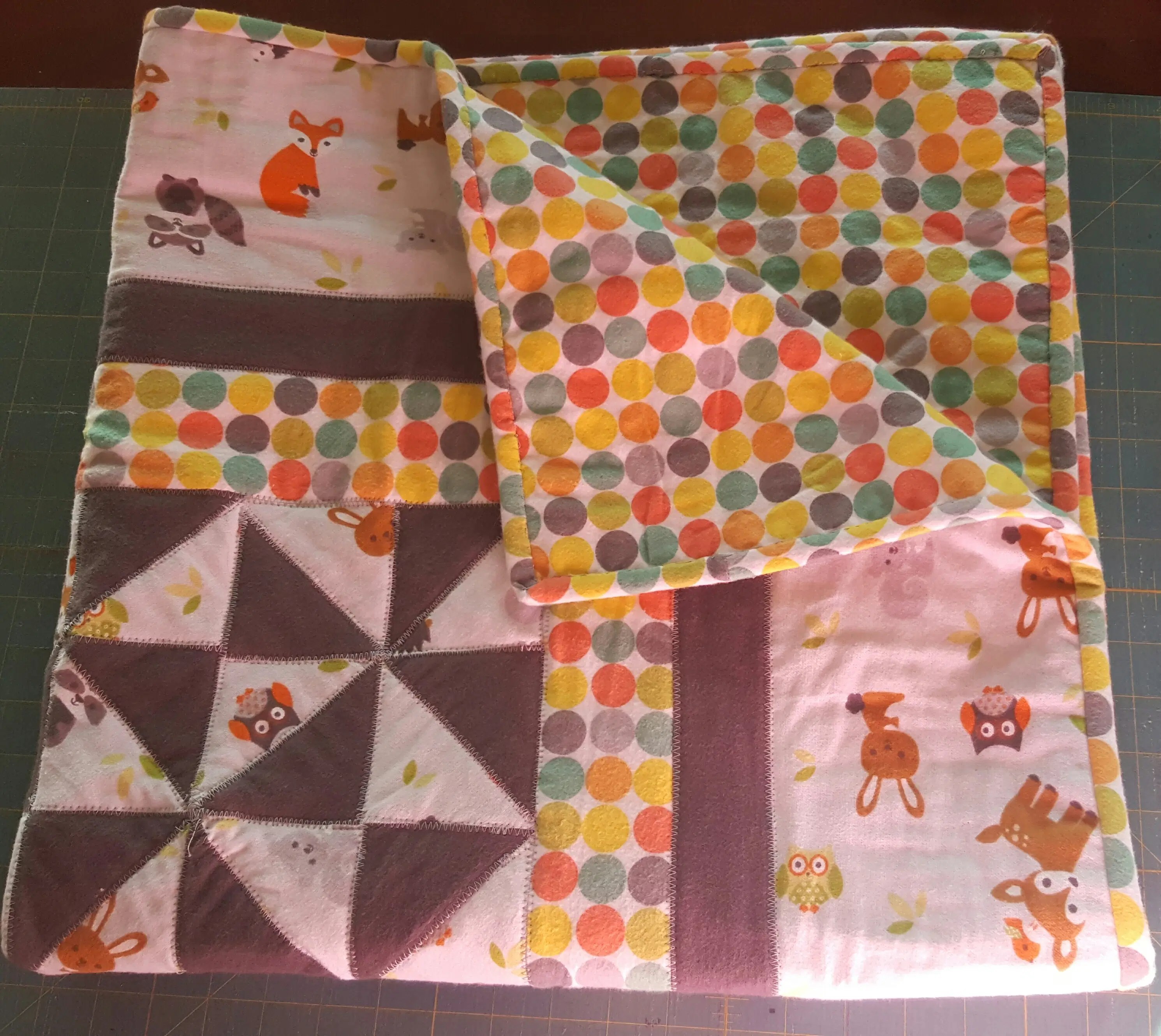 Soft, baby-size quilt featuring woodland animal prints and pastel dots.