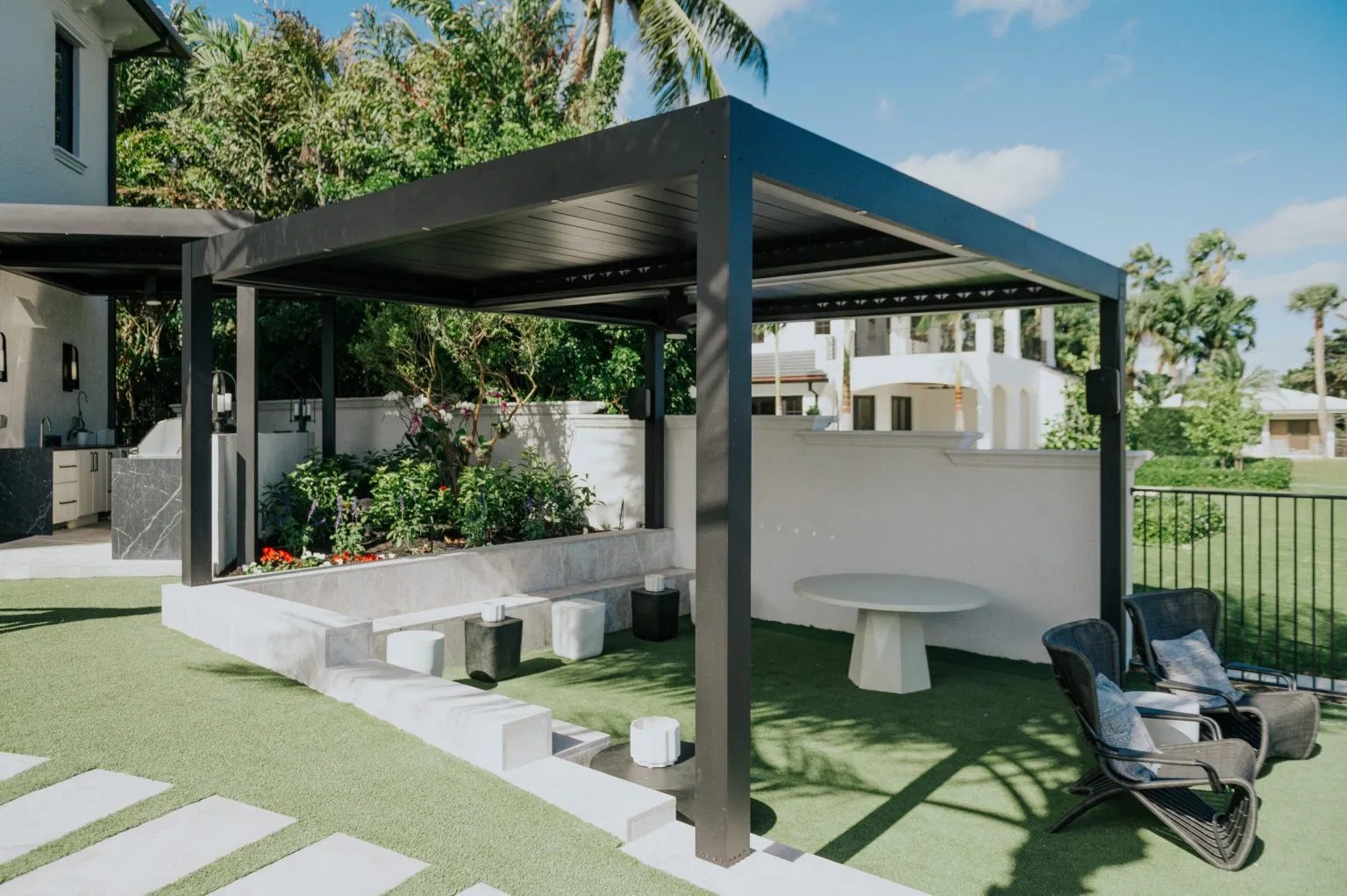 Sleek black aluminum louvered roof providing shade over a contemporary outdoor dining and seating area