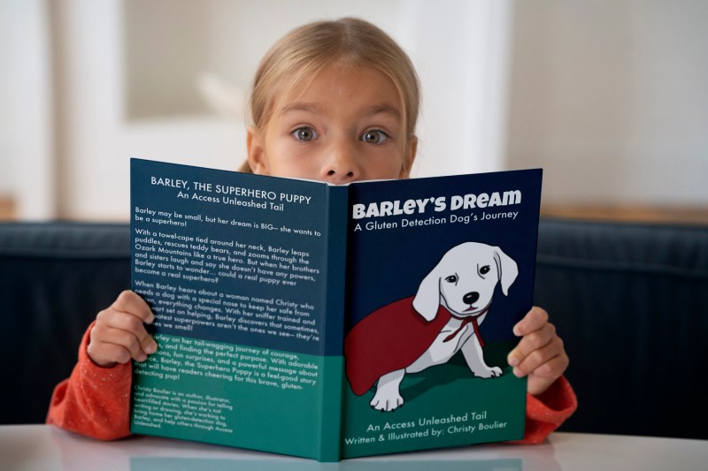 A child holding and reading Barley’s Dream, with the colorful puppy book cover visible