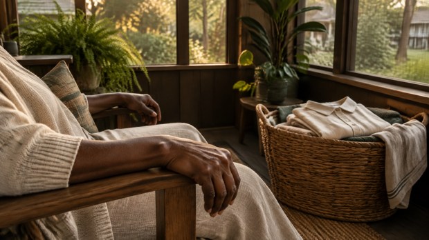 A quiet enclosed porch with a woven basket of freshly laundered clothes and a comfortable chair in warm late-afternoon light