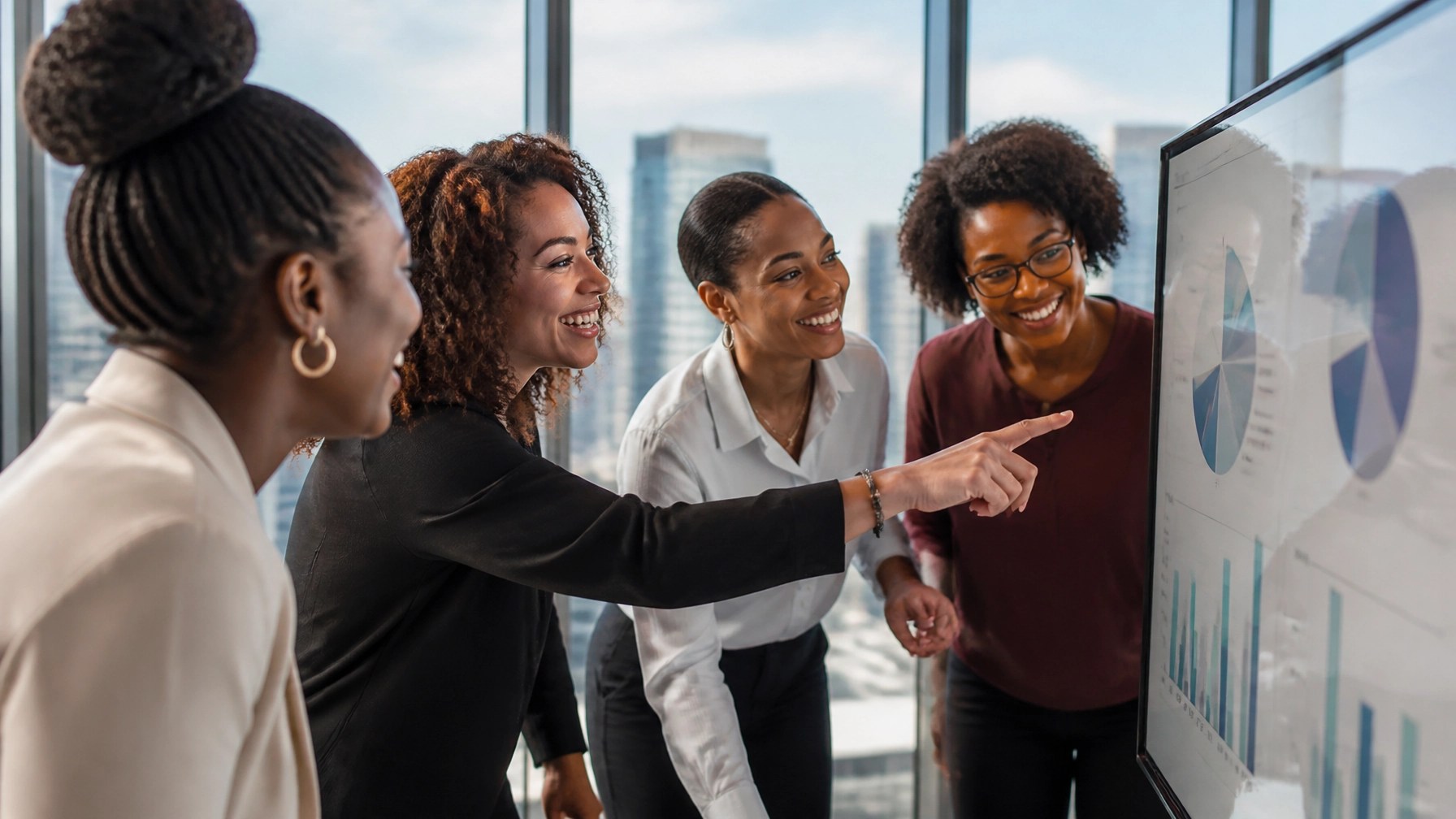 Diverse Black women entrepreneurs laughing and collaborating in a high-rise office
